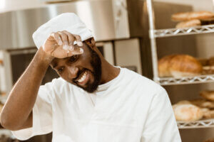 overworked african american baker wiping sweat on baking manufacture